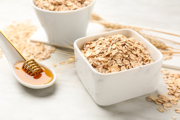 Bowl with oat flakes and honey on light table