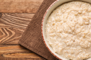 Bowl with tasty oatmeal on wooden table