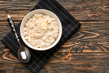 Bowl with tasty oatmeal on wooden table