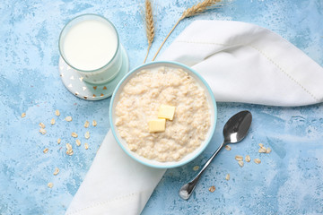 Bowl with tasty oatmeal and glass of milk on color background