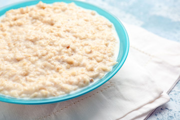 Bowl with tasty oatmeal on table