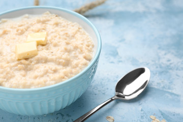 Bowl with tasty oatmeal on color background