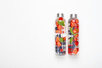 Bottles of tasty infused water on white background