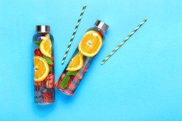 Bottles of tasty infused water on color background