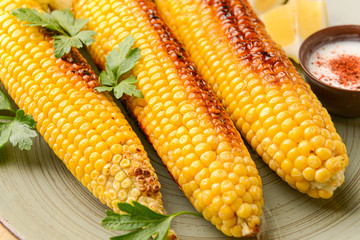 Tasty grilled corn cobs on plate, closeup