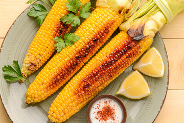 Tasty grilled corn cobs on plate