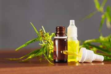Hemp plant herbal pharmaceutical CBD oil from jar. CBD oil bottles cannabis extract tincture liquid on wooden table. Medical marijuana concept