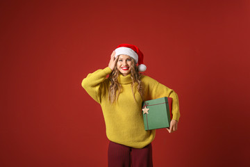 Beautiful young woman with Christmas gift on color background