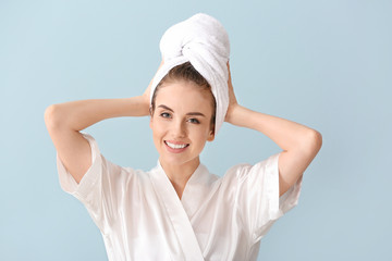 Beautiful young woman after washing hair against color background