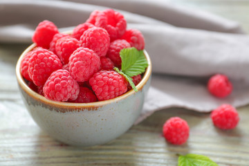 Bowl with tasty ripe raspberries on wooden table