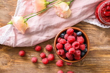 Bowl with tasty ripe berries and jam on wooden table