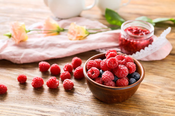 Bowl with tasty ripe berries on wooden table