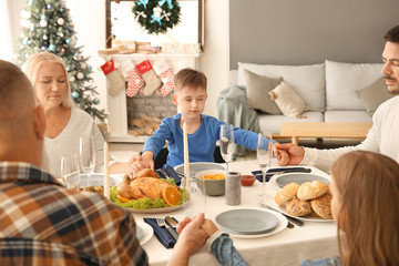 Obraz na płótnie Canvas Family praying before having Christmas dinner at home
