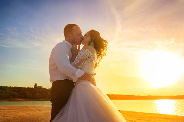 Romantic wedding couple on the shore. Bride with the groom in the summer on a background of a lake...