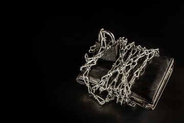 Male black chained purse is on the black background/table. There is the chain. Buy Nothing Day.