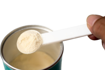 Powder milk and white spoon on white background close-up. Milk powder for baby in measuring spoon on can.