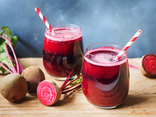 Glass of beetroot juice with red and white color  straw on rustic wooden table for healthy drinks...