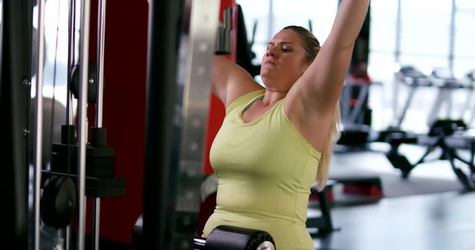 Plus Size Model, woman trains in Gym, lifting blocks on rack machine, training muscles on block device and gym equipment.