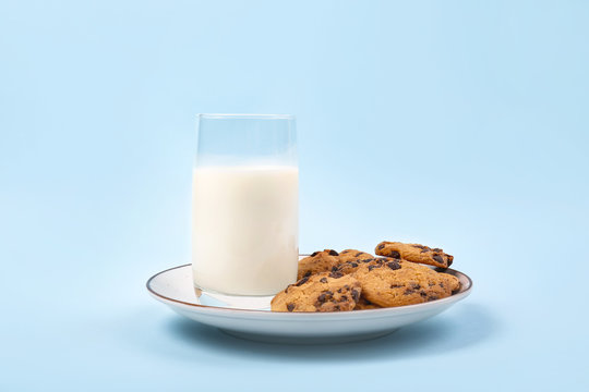 Plate with tasty cookies and glass of milk on color background