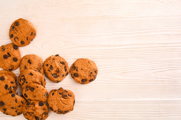 Tasty cookies with chocolate chips on light wooden background