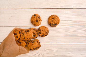 Tasty cookies with chocolate chips on light wooden background