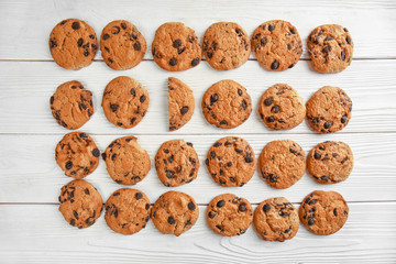 Tasty cookies with chocolate chips on light wooden background