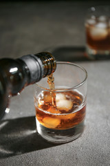Pouring of whiskey in glass on table