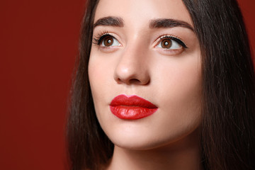 Beautiful young woman with bright lipstick on color background