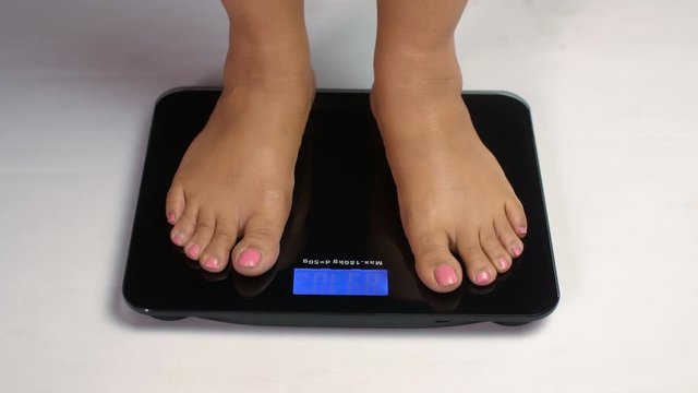 Indian female standing on a weight scale- Weight loss concept. Women's approaching and standing on body weight scales to measure weight loss. Close-up female legs - fitness concept