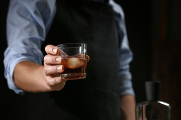 Barman with glass of whiskey in pub, closeup