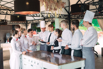 Restaurant manager and his staff in terrace. interacting to head chef in restaurant.