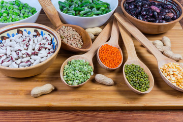 Various uncooked dried and frozen legumes on wooden cutting board