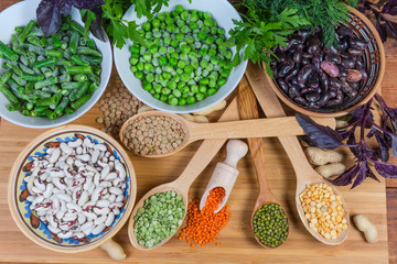 Top view of various uncooked dried and frozen legumes, greens