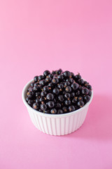 Ripe black currant or blueberries in a small white Cup on a pink background. Black currant harvest. Healthy food. vegetarian food.