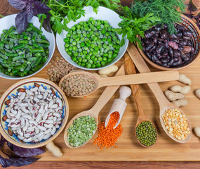 Top view of various uncooked dried and frozen legumes, greens