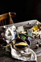 eggplants on metal vintage tray with basil, salt, knife on rustic wooden table