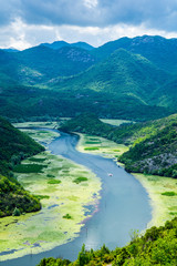 Montenegro, Tourists on boat trip on crnojevica river bend of pavlova strana water alongside green water lilly fields in national park of skadar lake