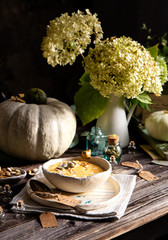 homemade pumpkin soup puree with pumpkin seeds in ceramic bowl on plate with spoon
