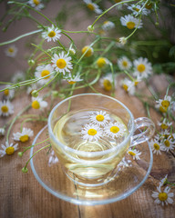 Fototapeta na wymiar Cup of chamomile herbal tea with flowers on a table. Healthy natural drink.