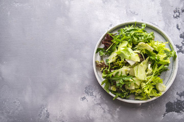 Mix of fresh greens on a plate. Fresh summer green salad. Top view. Copy space