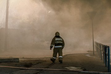 Firefighters extinguish a large house fire in smoke