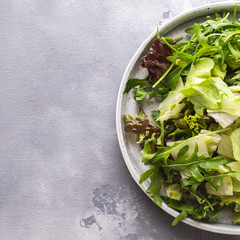 Mix of fresh greens on a plate. Top view.  Diet and healthy food