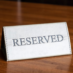 Reserved sign on a wooden table in a restaurant. Table setting with RESERVED sign