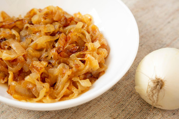 Homemade caramelized onions on a white plate, low angle view. Close-up.