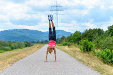 Agile woman doing a handstand on a rural road