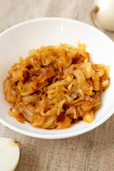 Homemade caramelized onions on a white plate, side view. Close-up.