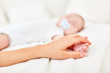 Obraz na płótnie Canvas Mom touches hand of sleeping baby