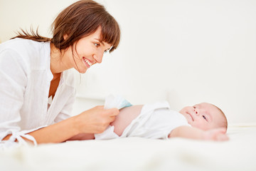 Smiling mother changes the diapers