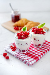 Two glasses with greek yogurt, raspberry and red currant