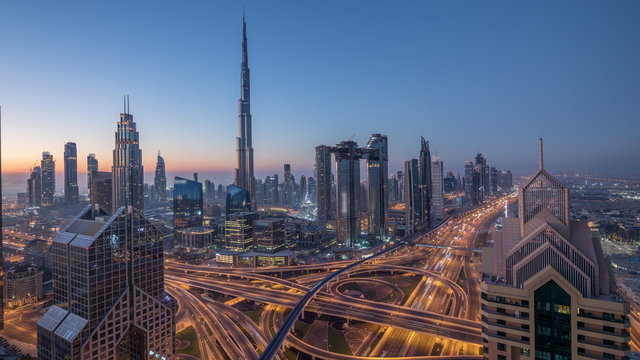 Dubai downtown skyline with tallest skyscrapers and busiest traffic on highway intersection night to day timelapse
